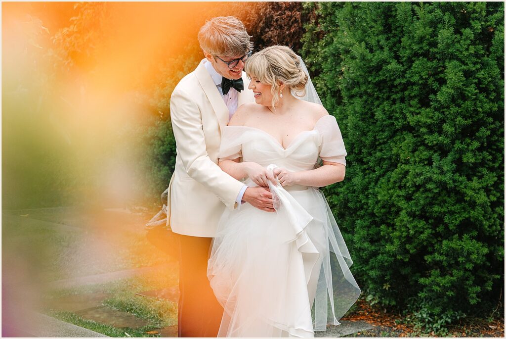 A groom puts his arm around a bride's waist.