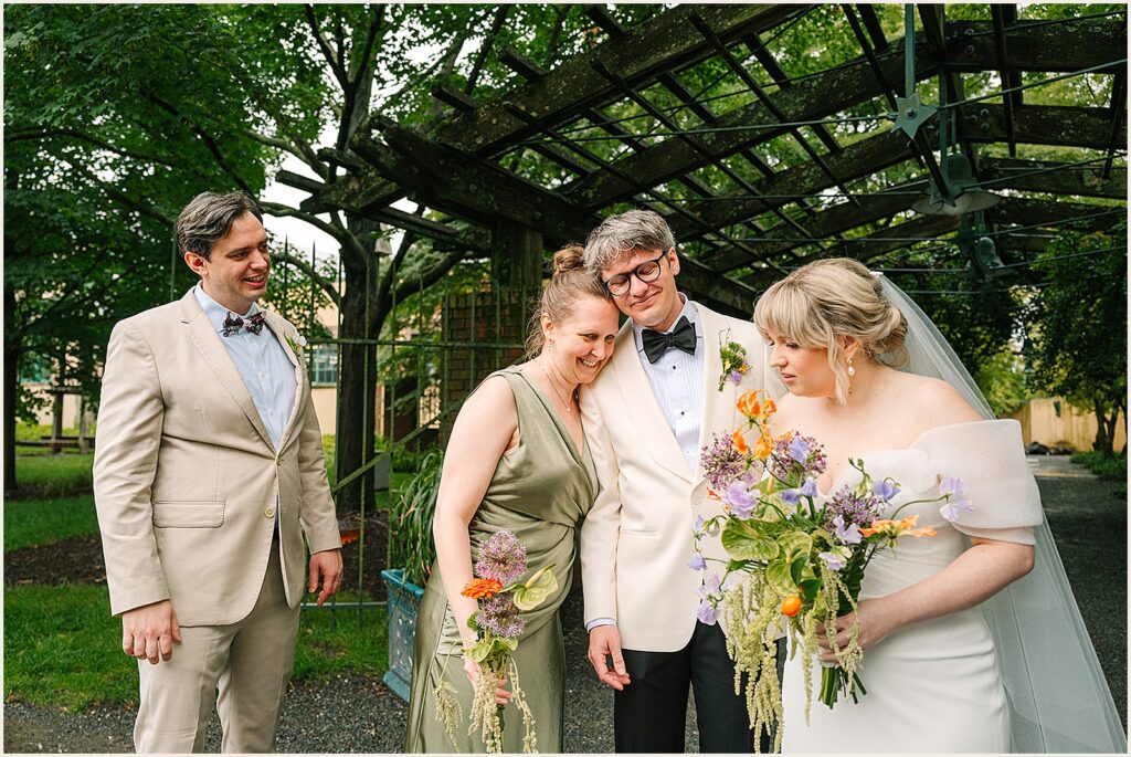 A groom hugs a bridesmaid under an arch.