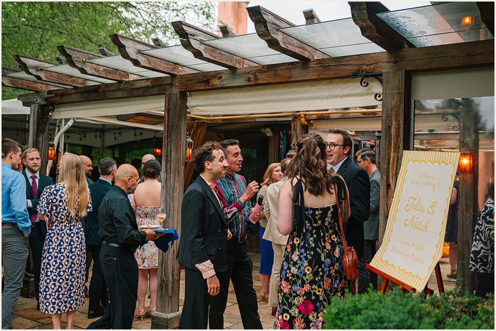 Wedding guests gather for cocktail hour on a patio.