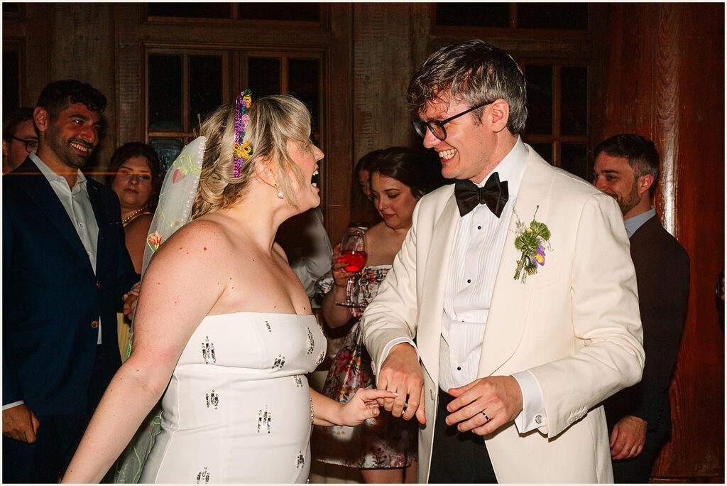 A bride and groom laugh while they dance.