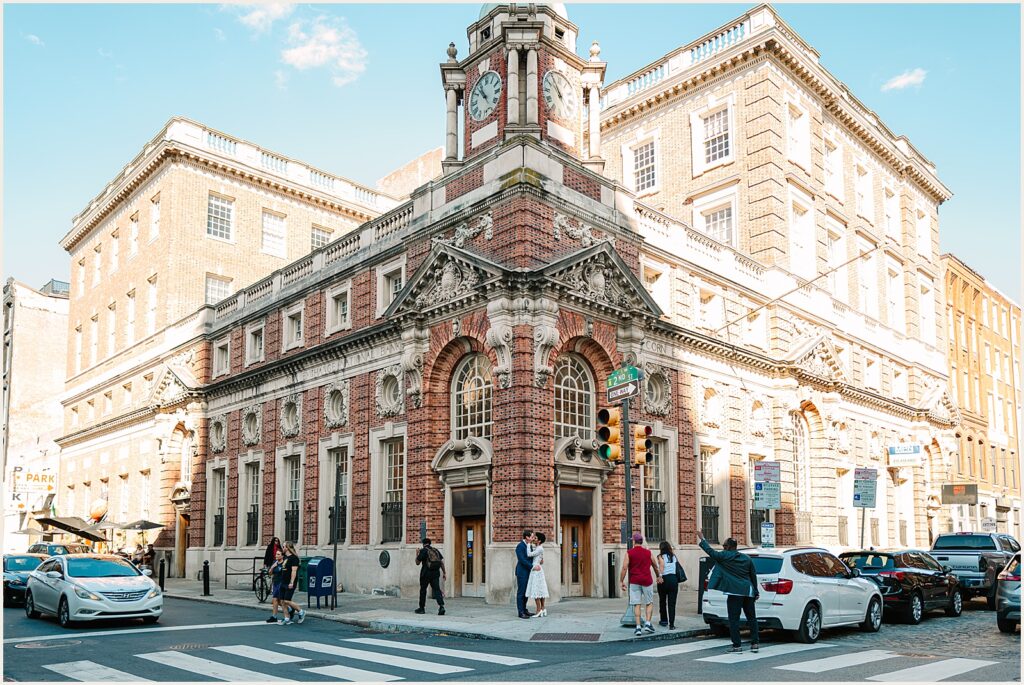 A bride and groom kiss in front of a historic building in Philadelphia.