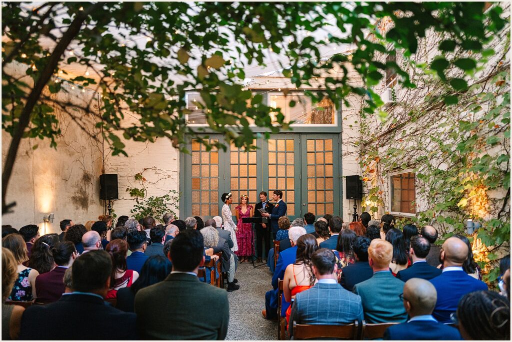 Guests sit in chairs to watch a wedding ceremony at the MAAS Building.