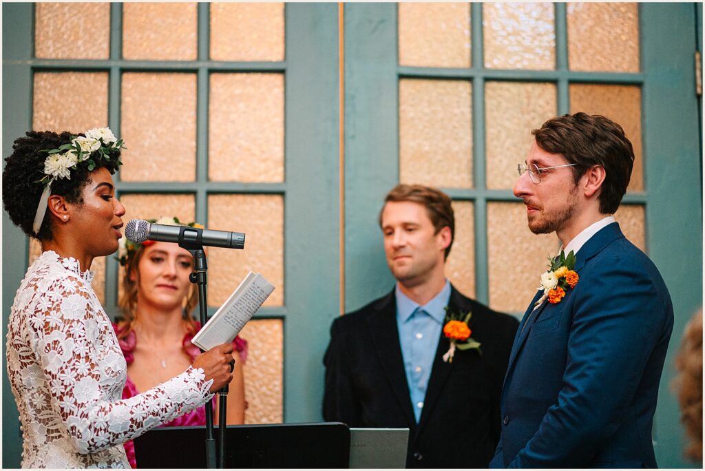 A bride reads vows from a notebook during a Philly wedding ceremony.