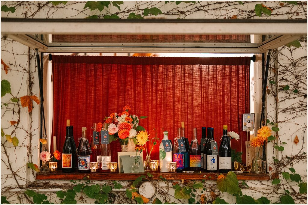 Wine and liquor bottles sit on a windowsill at a wedding reception.