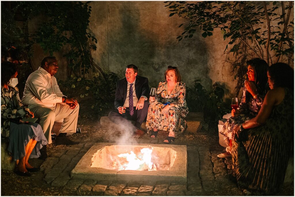 Wedding guests sit around a fire pit at the MAAS building.