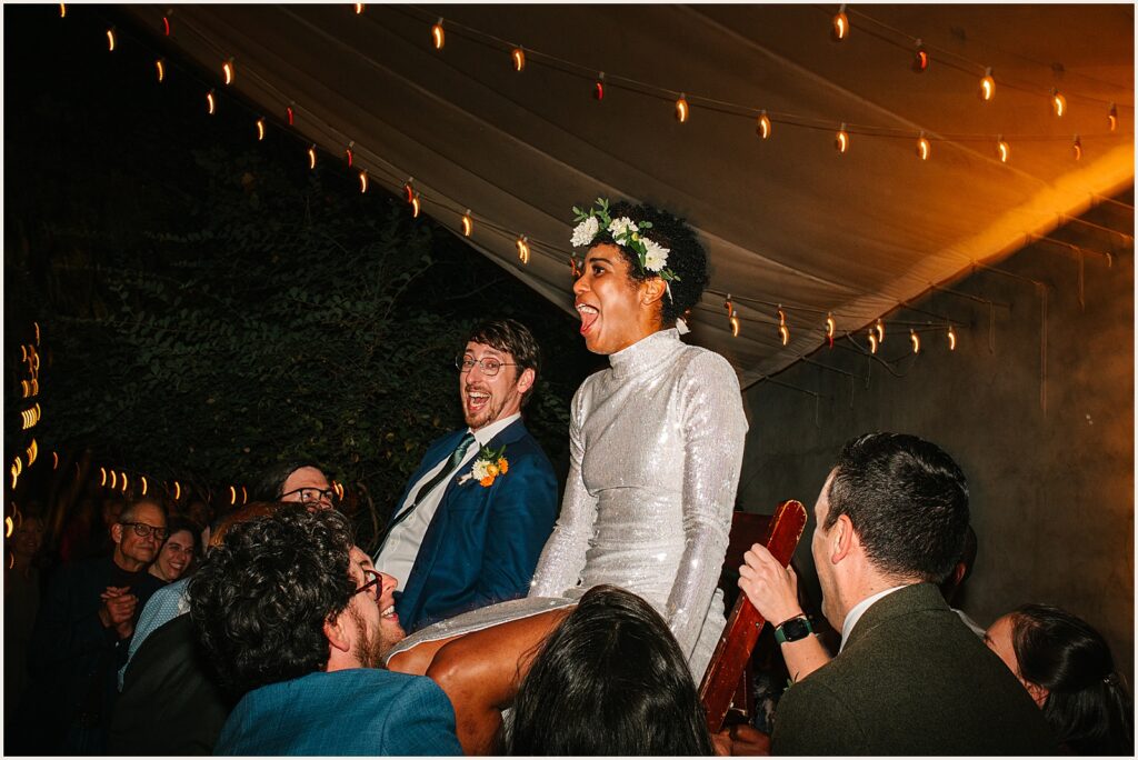 Guests lift a bride and groom for the hora
