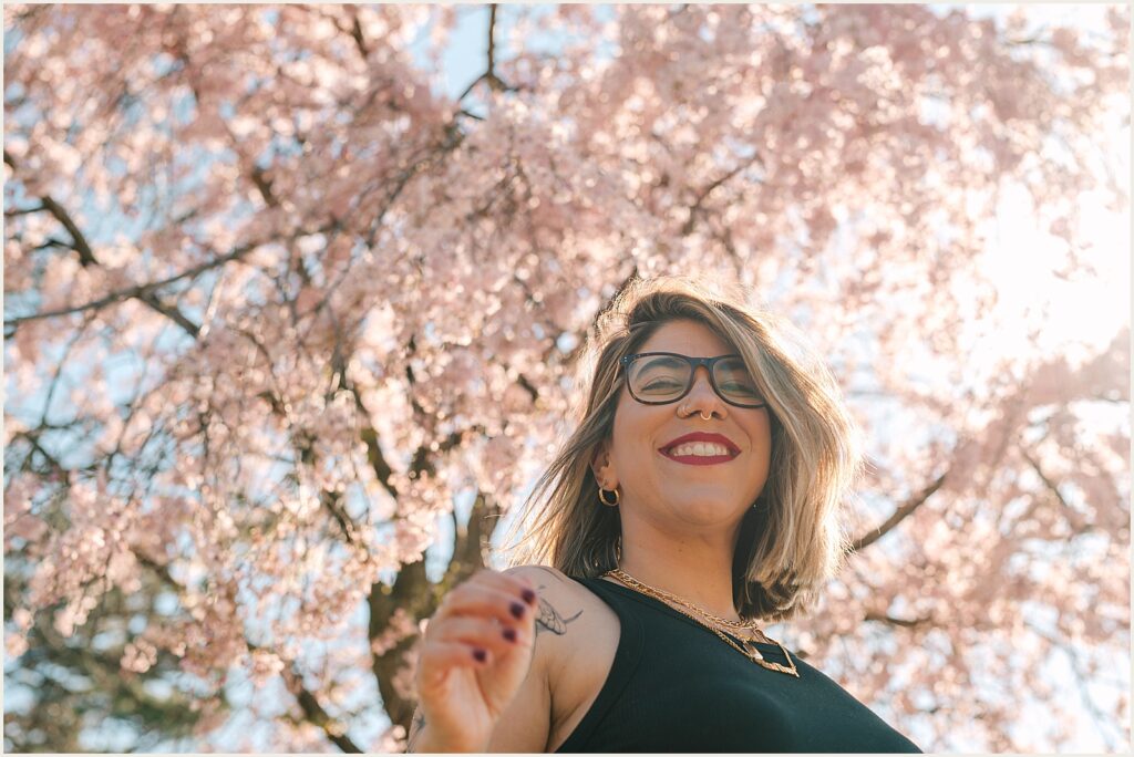 An author stands beneath a cherry tree smiling.
