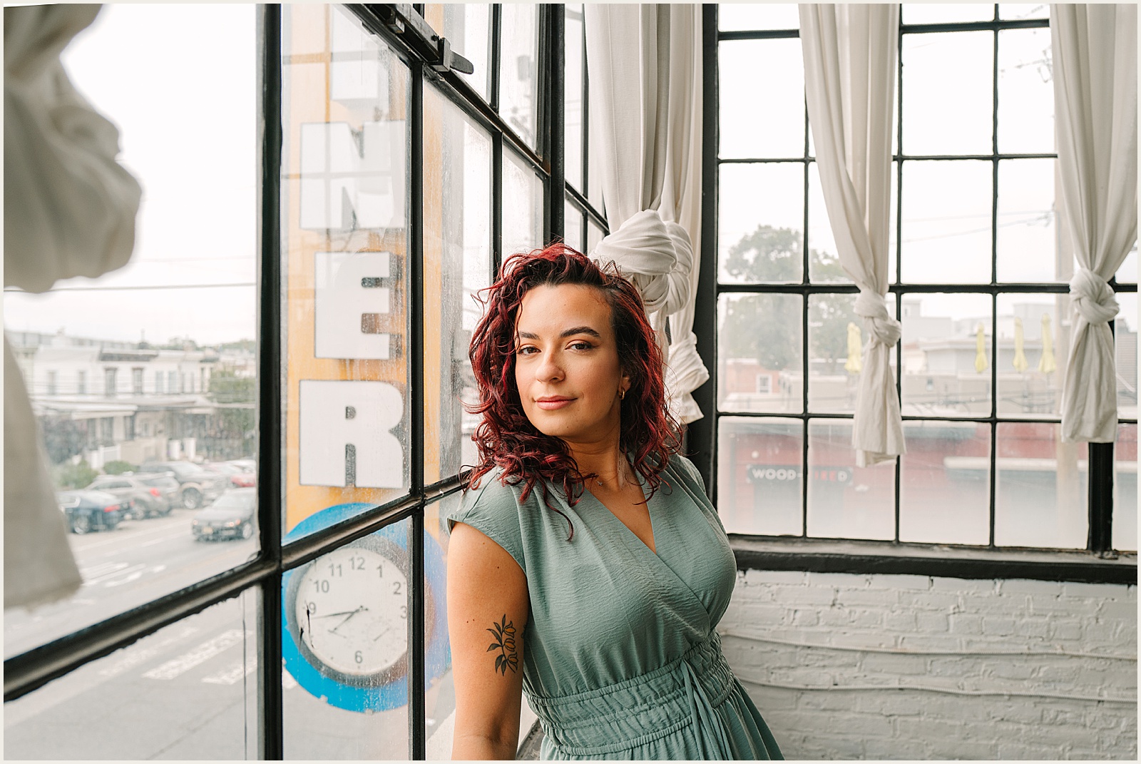 An author poses for headshots beside a wall of windows.