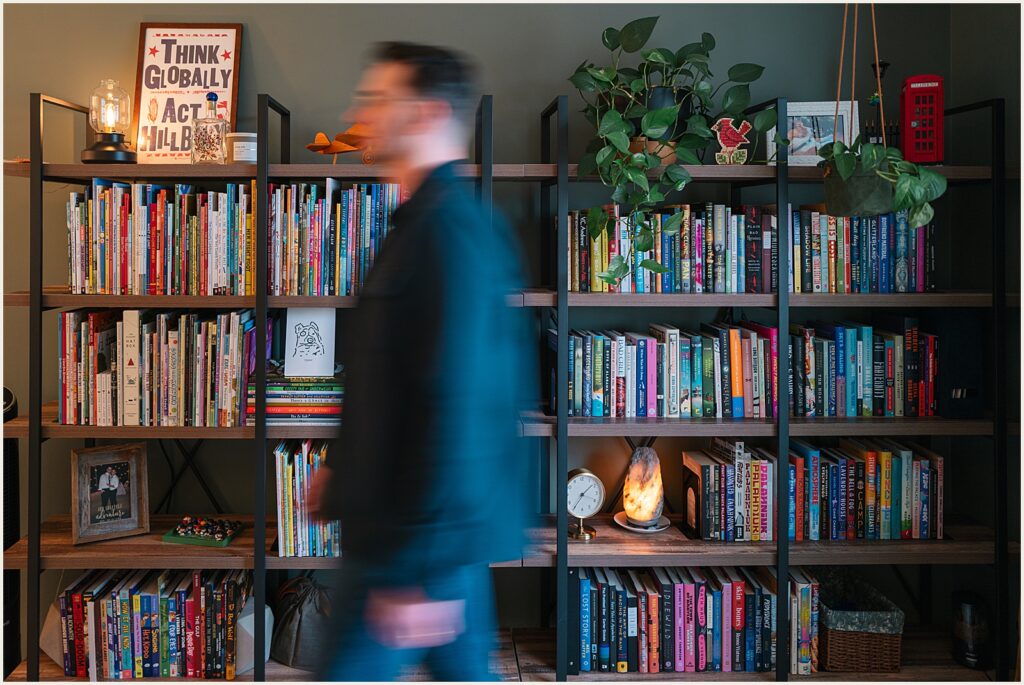 An author walks past a bookshelf in his Philadelphia office.