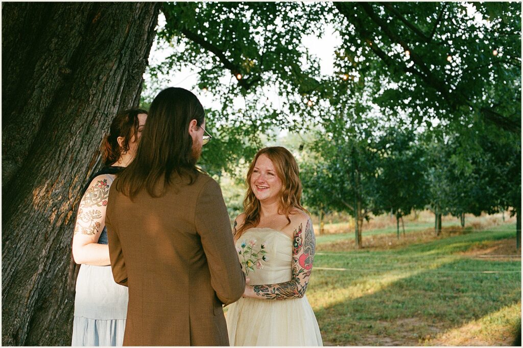 A bride smiles at a groom during a wedding ceremony.