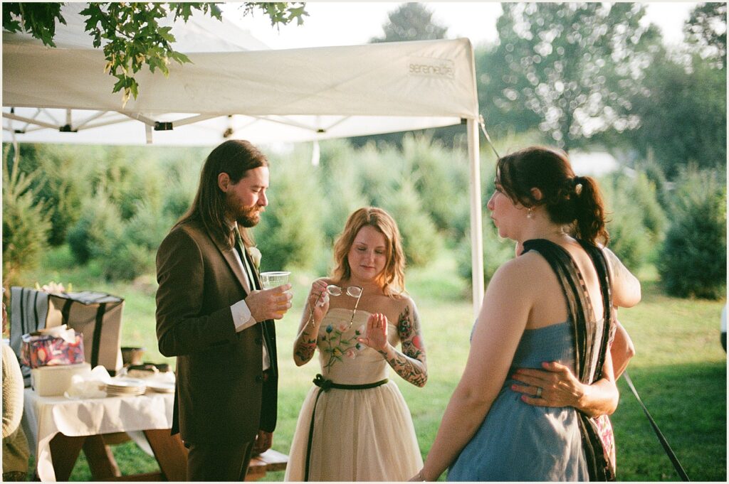 A bride cleans a groom's glasses.