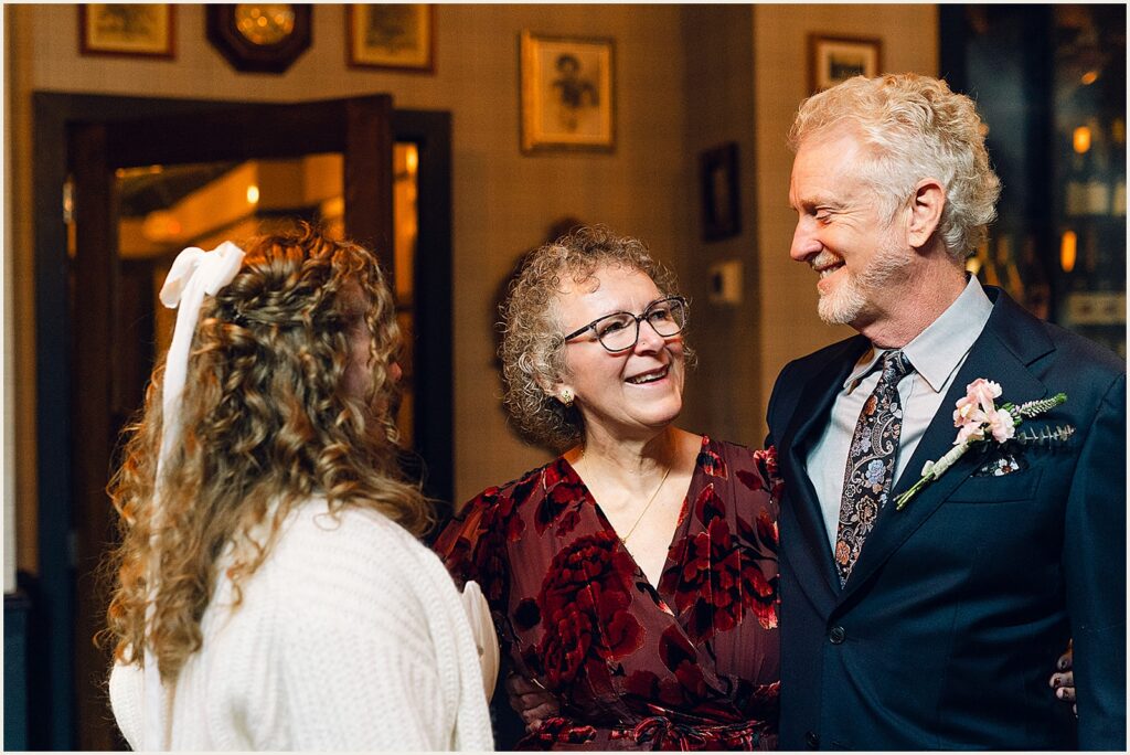 A bride stands with her smiling parents.