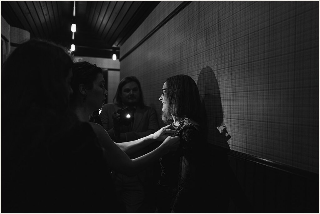 Women adjust their clothes in a hallway.