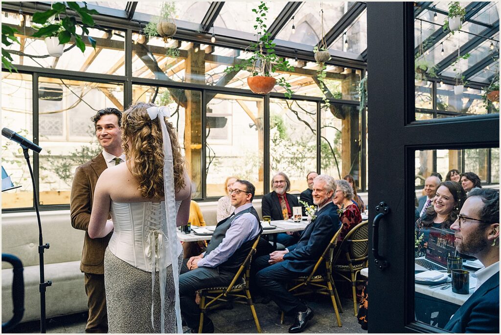 Wedding guests sit at tables watching a brunch wedding ceremony.