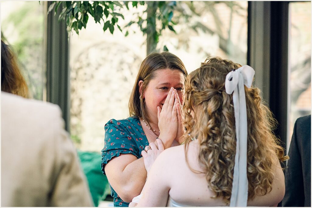 A wedding guest covers her face when she talks to a bride.