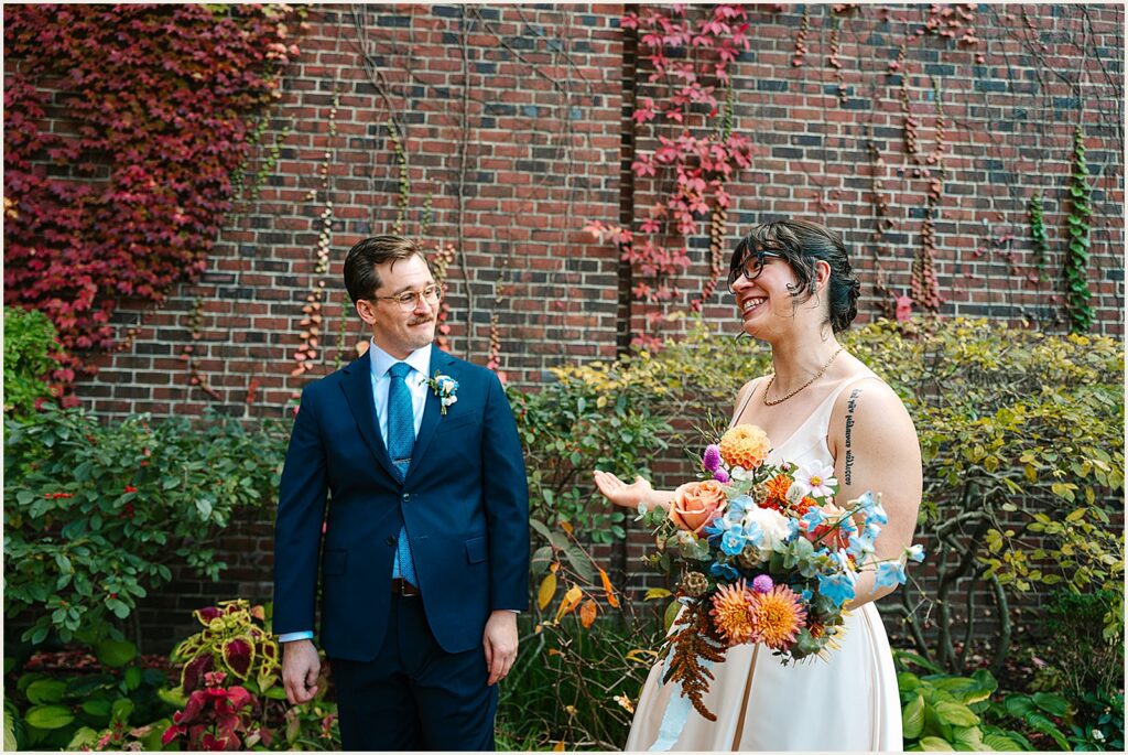 A bride and groom laugh while they walk down the sidewalk.