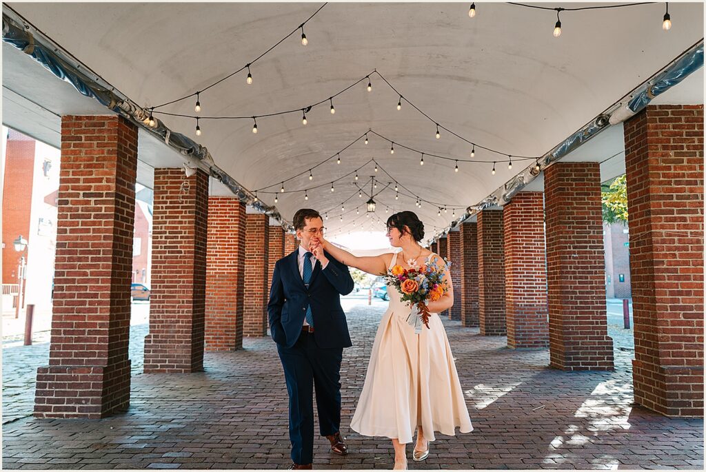 A groom kisses a bride's hand on a Philadelphia sidewalk.