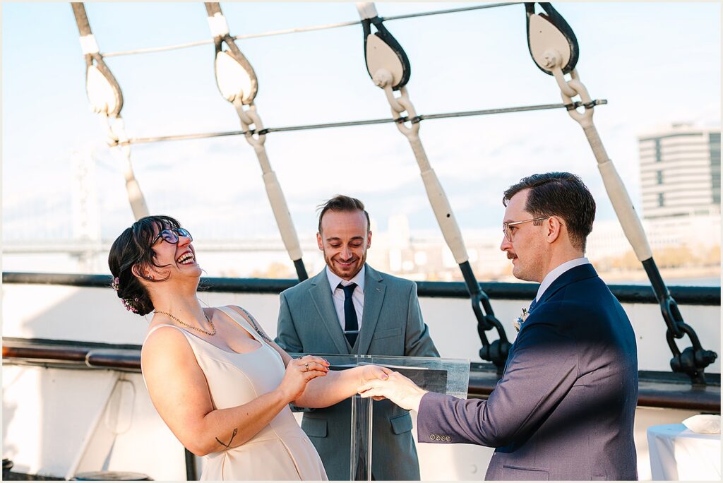 A groom puts a ring on a bride's hand.