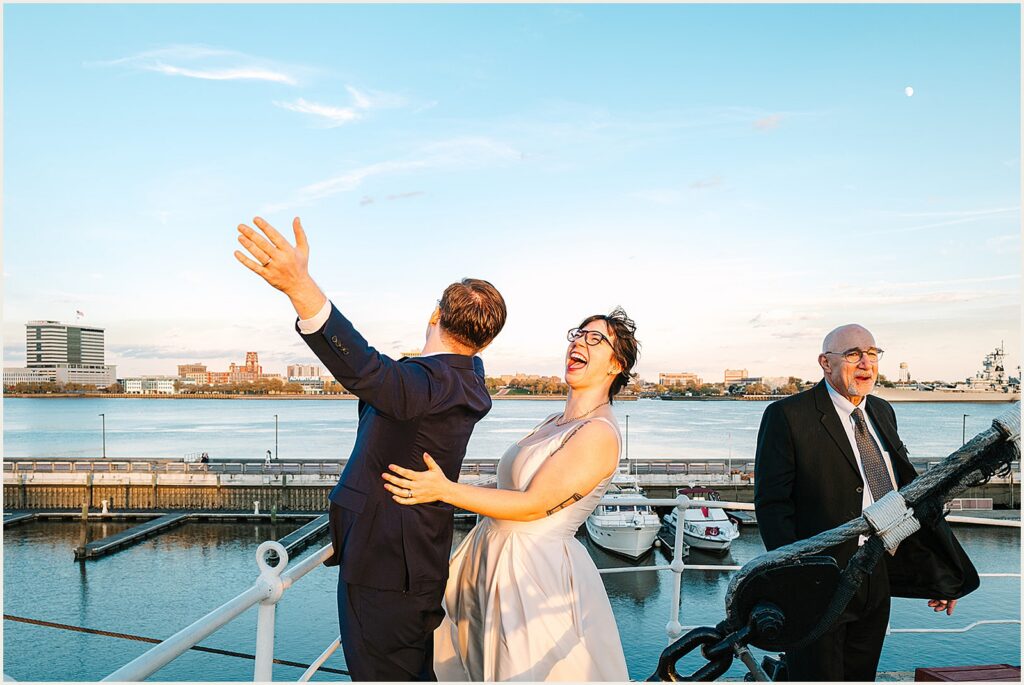 A bride and groom pose for a silly photo on a boat.