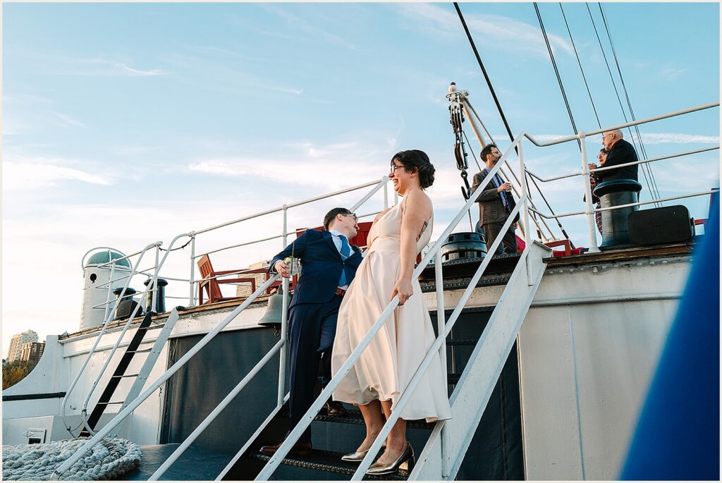 A bride and groom laugh as they walk down a flight of stairs.