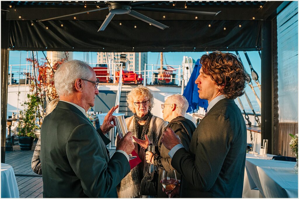 Wedding guests gather on deck to talk.