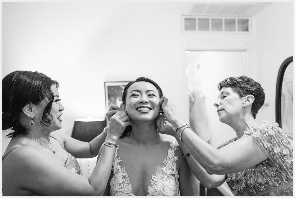 A bride smiles as her family helps her do her hair.