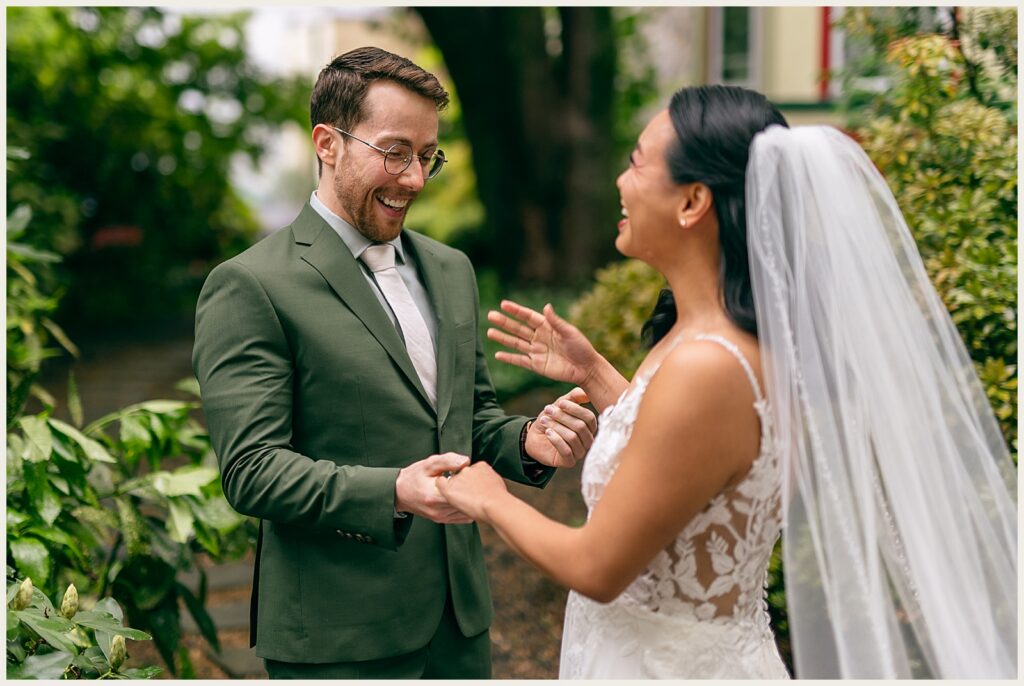 A bride and groom smile and admire each other's wedding attire.