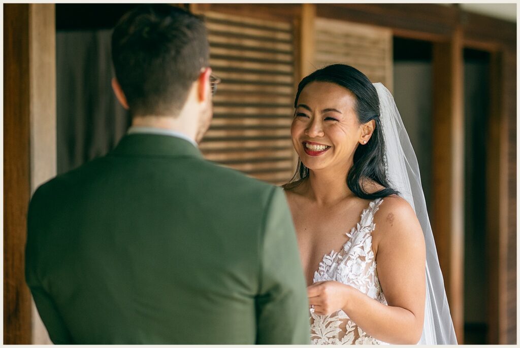 A bride laughs as a groom reads his vows.