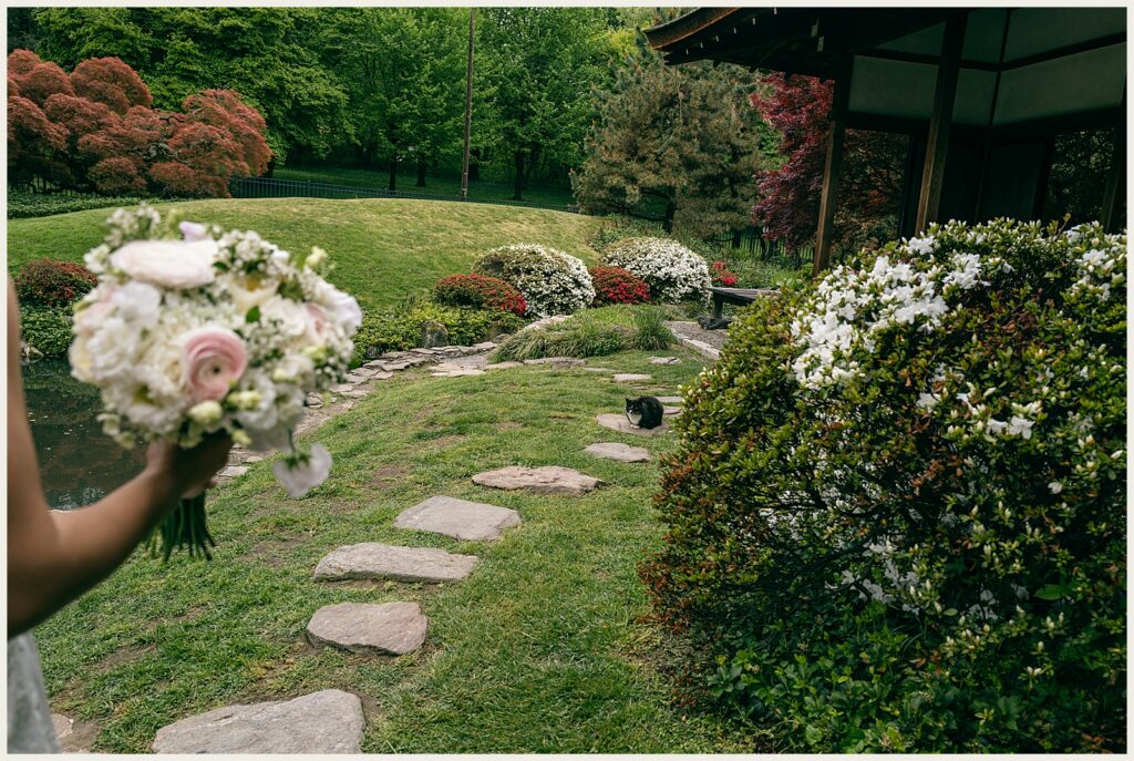 A bride carries a bouquet up a stone path.