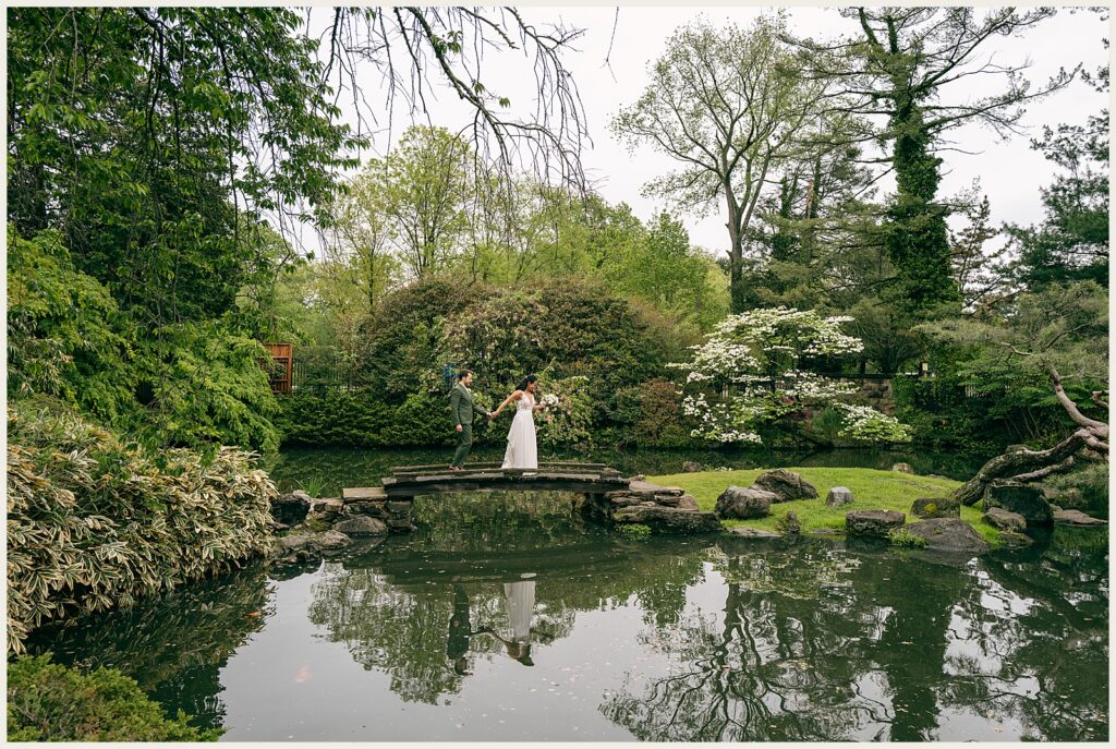 A bride and groom walk beside a pond at a Shofuso Japanese Garden wedding.