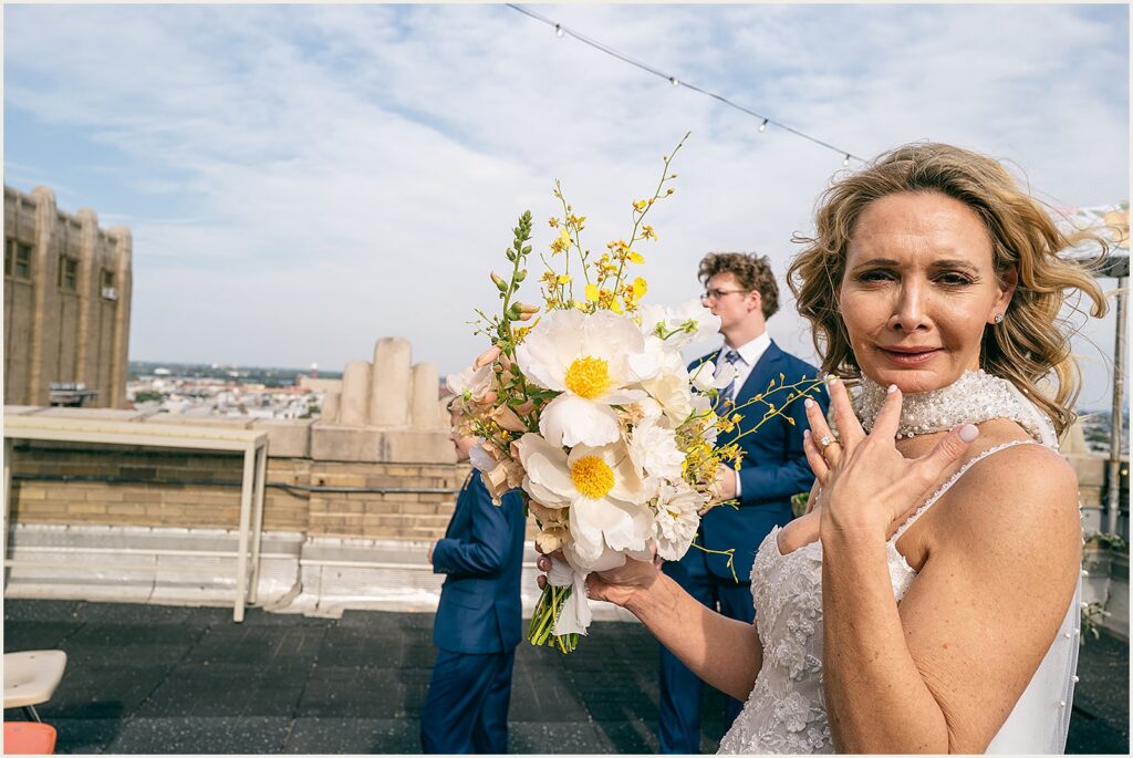 A bride holds a bouquet on a rooftop.