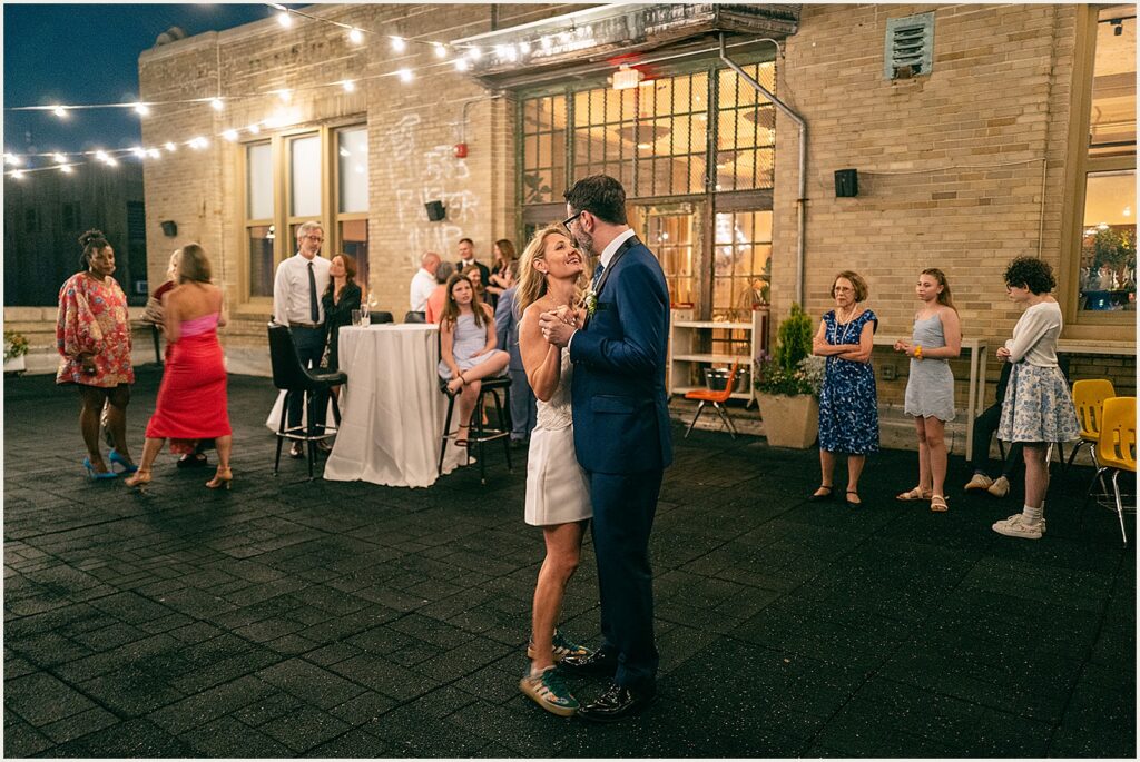 A bride and groom dance on a rooftop.